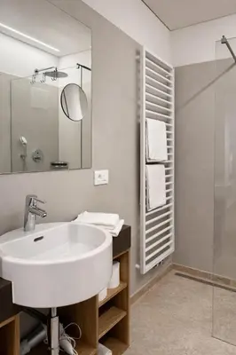 a white bathroom with a sink and a shower at Hotel Gartenresidence Zea Curtis in Merano