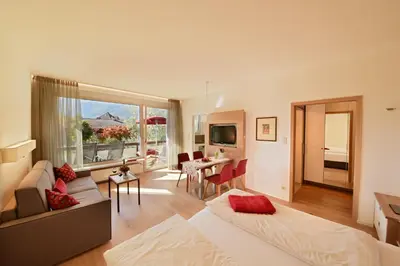 a hotel room with two beds and a living room at Hotel Gartenresidence Zea Curtis in Merano