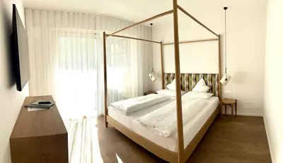 a bedroom with a canopy bed and a table at Hotel Gartenresidence Zea Curtis in Merano