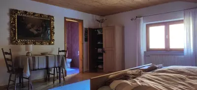a bedroom with a bed and a table and a window at Villa for a get away in Soprabolzano