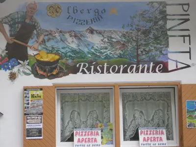a sign on the side of a restaurant with a painting at Albergo Pineta in Castello di Fiemme