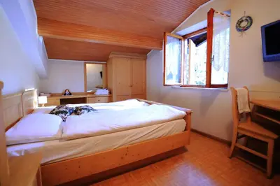 a bedroom with a bed and a desk and a window at Albergo Pineta in Castello di Fiemme