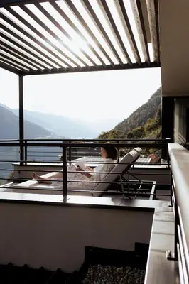 a woman sitting in a chair on a balcony with a view at Culinaria living in Tirolo