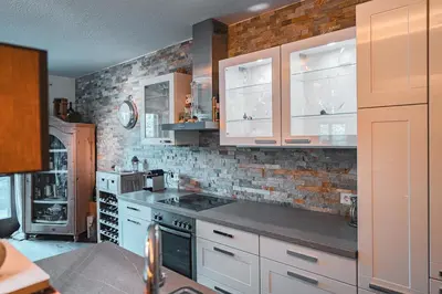 a kitchen with white cabinets and a brick wall at Majestic Apartment by Majestic Resorts Dolomites in Riscone