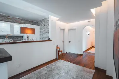 a kitchen with white cabinets and a brick wall at Majestic Apartment by Majestic Resorts Dolomites in Riscone