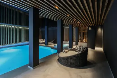 a room with a swimming pool and a bench next to a tub at Laurena Aparthotel in Naz-Sciaves
