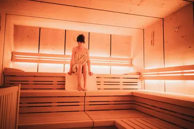 a woman sitting on a bench in a sauna at Laurena Aparthotel in Naz-Sciaves