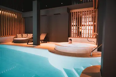 a bath room with a tub next to a pool at Laurena Aparthotel in Naz-Sciaves