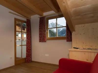a living room with a red couch and a window at Appartments Jagerhof in Braies