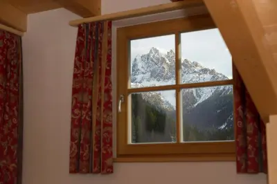 a window with a view of a snow covered mountain at Appartments Jagerhof in Braies