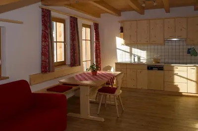 a kitchen with a table and a red couch at Appartments Jagerhof in Braies