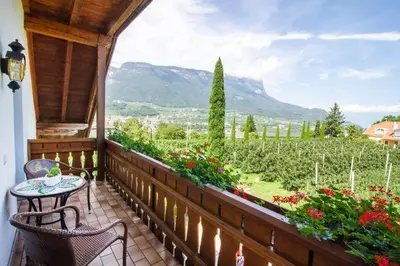 a porch with a table and chairs and flowers at Marolhof in Cornaiano