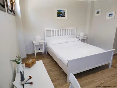 a white bedroom with a white bed and two tables at Pordoi H10 - with SAUNA in Alba di Canazei