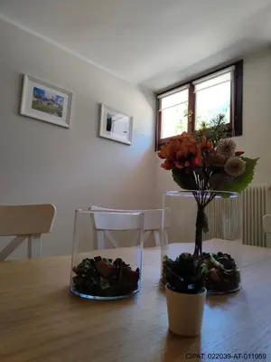 a wooden table with a vase with flowers on it at Pordoi H10 - with SAUNA in Alba di Canazei