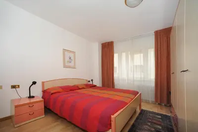 a bedroom with a bed and a dresser and a window at Appartamento Dolomiti in Predazzo