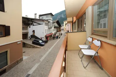 a balcony with two chairs on a city street at Appartamento Dolomiti in Predazzo
