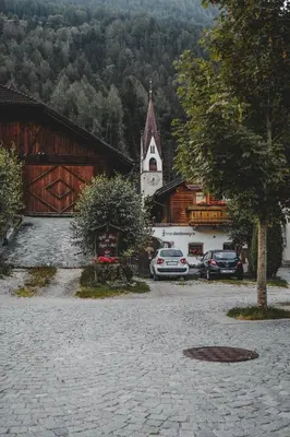 a church with a clock tower next to a parking lot at Luggishof in Campo Tures