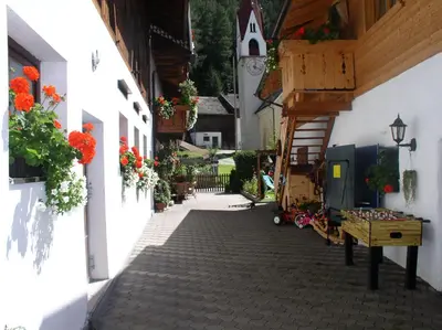 a street in a village with flowers on the buildings at Luggishof in Campo Tures