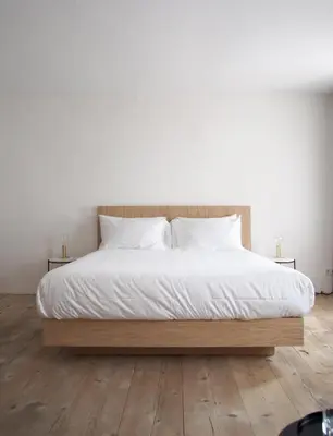 a bed with white sheets and pillows on a wooden floor at Marktplatz 10 in Caldaro