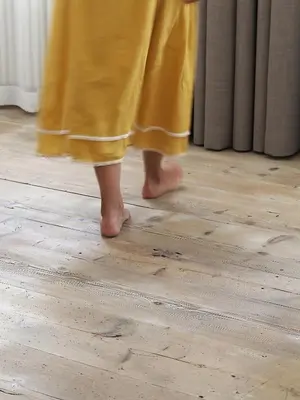 a woman in a yellow dress walking on a wooden floor at Marktplatz 10 in Caldaro