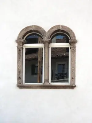 two windows on a white wall with a table at Marktplatz 10 in Caldaro