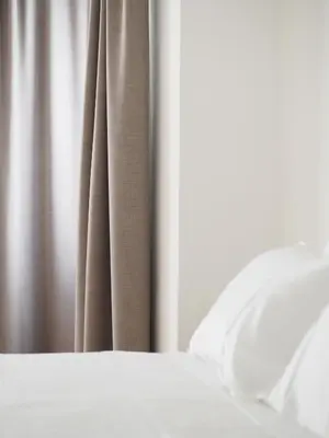 a bed with white sheets and a curtain at Marktplatz 10 in Caldaro