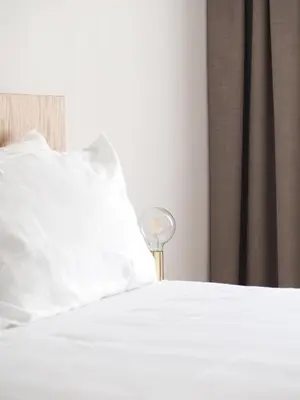 a white bed with a white pillow and a lamp at Marktplatz 10 in Caldaro