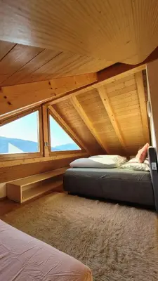 an attic room with two beds and two windows at Apartment Frisch in San Lorenzo di Sebato