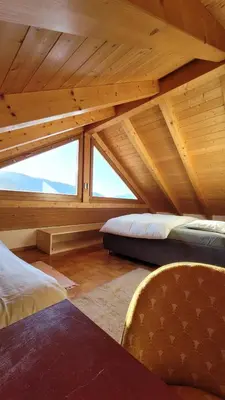 a attic room with two beds and a chair at Apartment Frisch in San Lorenzo di Sebato