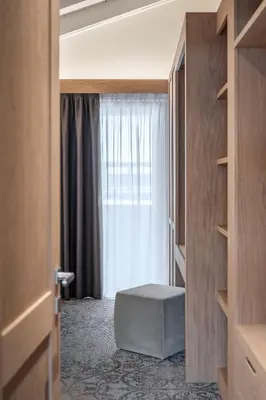 a room with a window and a stool in front of a door at Hotel Lajadira & Spa in Cortina dʼAmpezzo