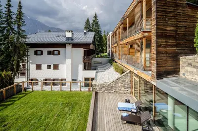 a balcony of a house with chairs and a yard at Hotel Lajadira & Spa in Cortina dʼAmpezzo