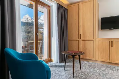 a room with a blue chair and a table and a window at Hotel Lajadira & Spa in Cortina dʼAmpezzo