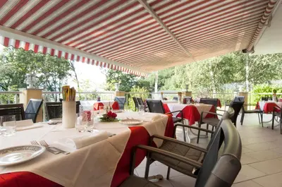 a dining room with tables and chairs with red tablecloths at Hotel Rotwand in Laives
