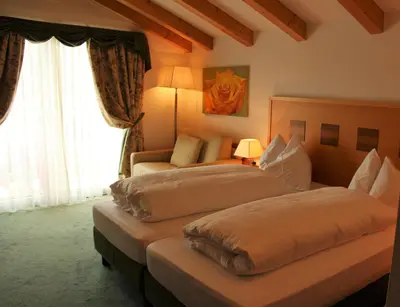 a hotel room with two beds and a couch at Hotel Rotwand in Laives
