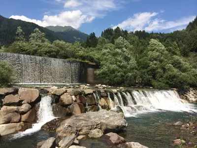 a waterfall in a river next to a stone wall at Appartamento Vanoi nel cuore verde del Trentino in Canale San Bovo