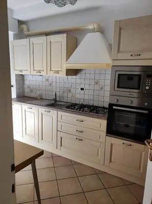 a kitchen with white cabinets and a stove top oven at Appartamento Vanoi nel cuore verde del Trentino in Canale San Bovo