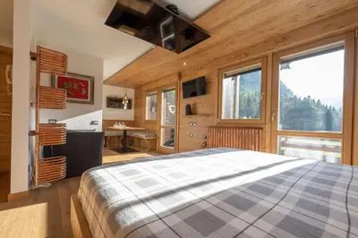 a bedroom with a large bed and a desk andwindows at Cesa Ardon 1 in Campitello di Fassa
