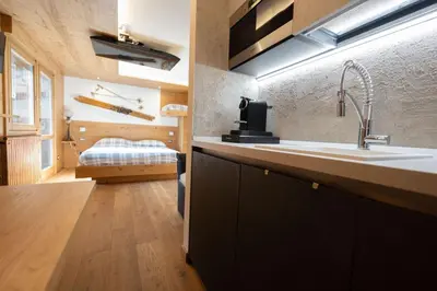 a kitchen with a sink and a bed in a room at Cesa Ardon 1 in Campitello di Fassa
