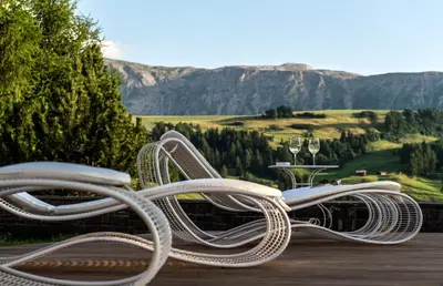 a couple of chairs sitting on a deck with a view at Hotel Rosa Eco Alpine Spa in Alpe di Siusi