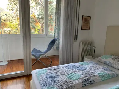 a bedroom with a bed and a chair and a window at Villa Doris in Merano