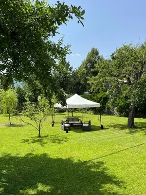 a picnic table with a white canopy in a field at Dolomitihouse BEDOL in Fiera di Primiero