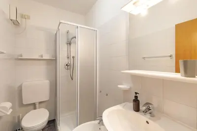 a white bathroom with a toilet and a sink at Dolomitihouse BEDOL in Fiera di Primiero