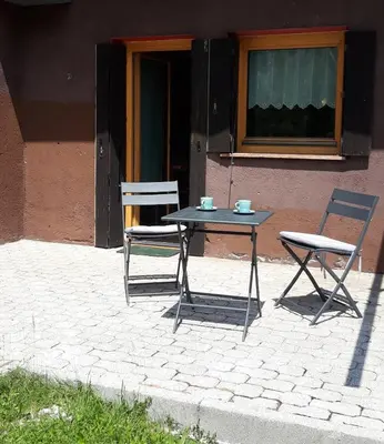 a table and two chairs sitting next to a building at La Casa degli Gnomi in Falcade