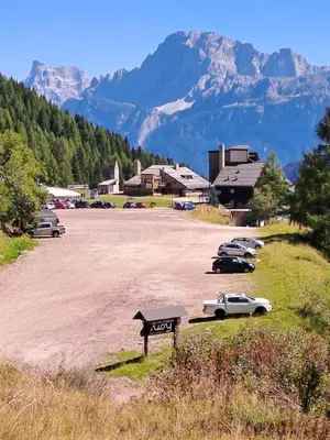 a parking lot with cars parked in front of a mountain at La Casa degli Gnomi in Falcade