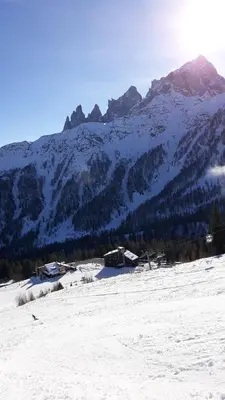 a snow covered mountain with a house in the foreground at La Casa degli Gnomi in Falcade
