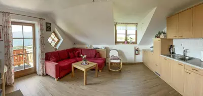 a living room with a red couch and a kitchen at Kuenhof in San Sigismondo