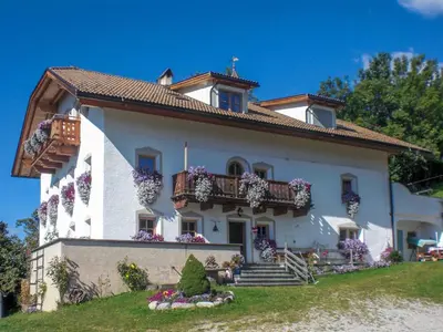 a large white house with flowers on the balcony at Kuenhof in San Sigismondo