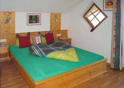 a bedroom with a bed with green sheets and colorful pillows at Kuenhof in San Sigismondo