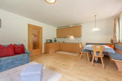 a living room with a blue couch and a kitchen at Bad Bergfallerhof in Valdaora