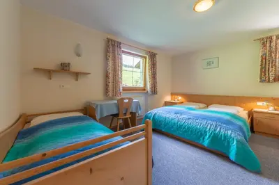 a bedroom with two beds and a table in it at Bad Bergfallerhof in Valdaora